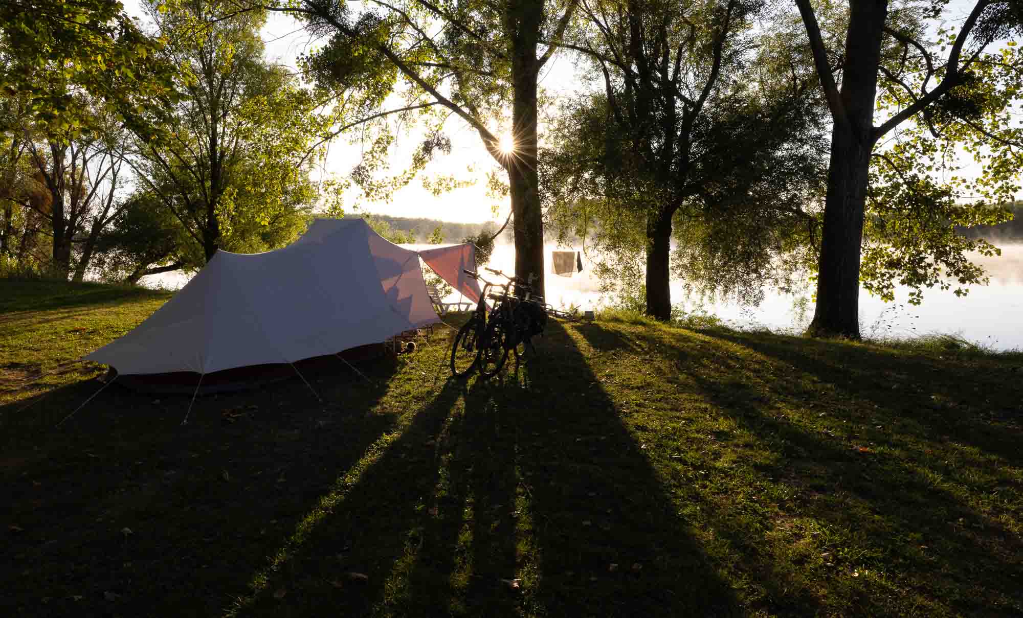 Tente au bord d'une rivière au lever du soleil, Camping des Fleurs