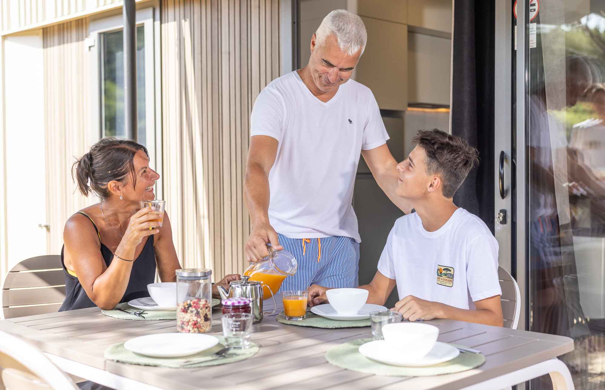 Famille prenant le petit-déjeuner sur la terrasse d'un mobil-home au Camping des Fleurs